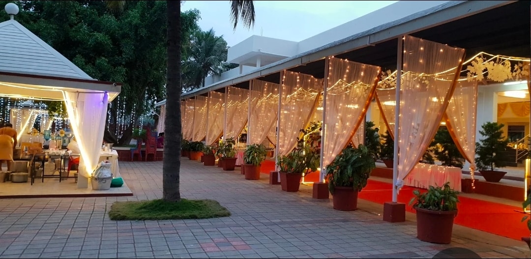 Covered veranda walkways with fairy-light drapes leading to family cottages at Kalathur Gardens
