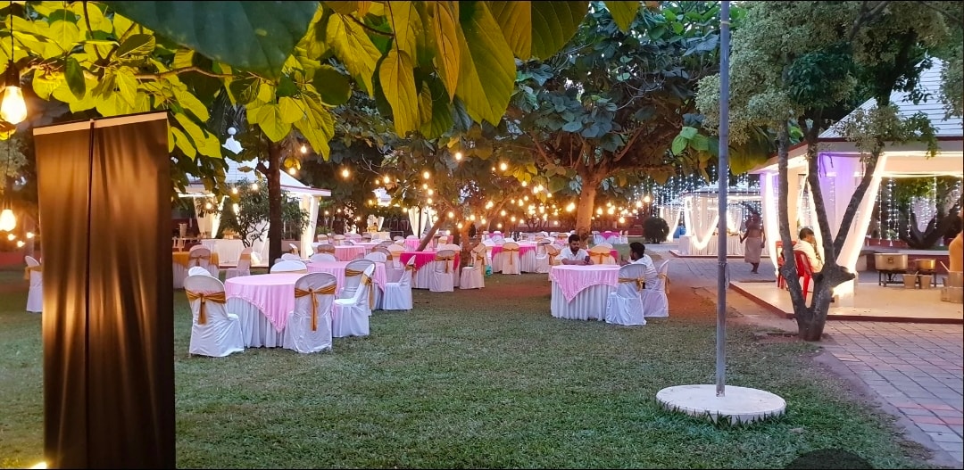 Outdoor banquet tables under fairy-lit trees at Kalathur Gardens